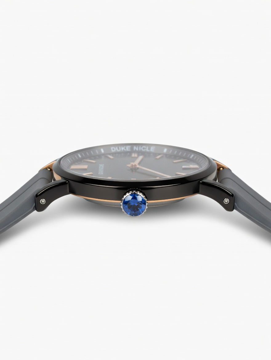 Duke Nicle men's wristwatch side view showing blue gemstone crown, silver case accents, and gray silicone strap on a clean white background