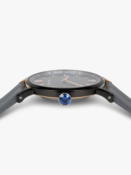 Duke Nicle men's wristwatch side view showing blue gemstone crown, silver case accents, and gray silicone strap on a clean white background