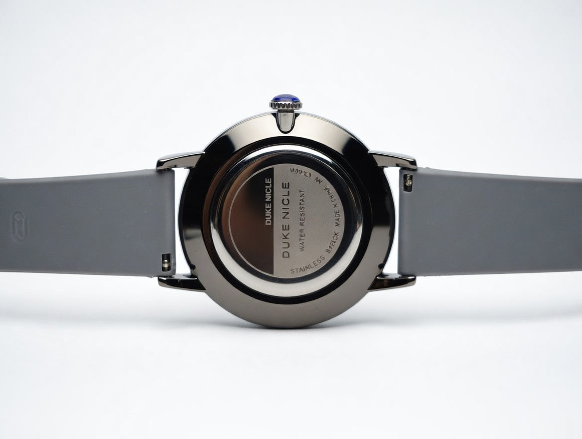 Duke Nicle men's wristwatch case back view showing stainless steel back with engraving, water resistant marking, and gray silicone strap on a clean white background
